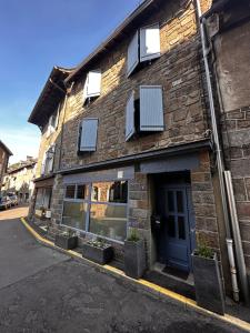 a brick building with windows and plants in front of it at La Maison aux Volets Bleus 3ème Étage in Vic-sur-Cère