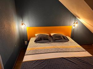 a bedroom with a bed with an orange headboard and two pillows at La Maison aux Volets Bleus 3ème Étage in Vic-sur-Cère