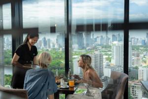 two women sitting at a table in a restaurant at Montraj Continent Sukhumvit Bangkok in Bangkok