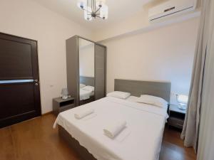 una camera con letto bianco e specchio di Apartments by GR Yerevan in the city centre a Yerevan