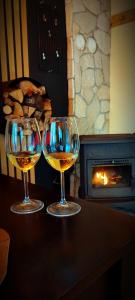 two wine glasses sitting on a table in front of a fireplace at Uki & Sofi mountain house in Kopaonik