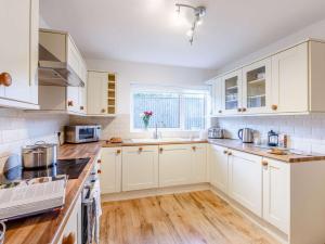 a kitchen with white cabinets and wooden floors at 3 Bed in Torquay 82959 in Torquay