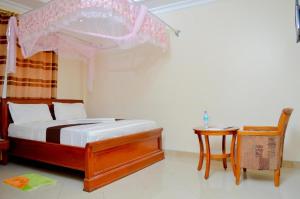 فندق سيلفر بارادايس في دار السلام: غرفة نوم بسرير مظلة مع طاولة وكرسي