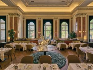 una sala da pranzo con tavoli, sedie e finestre di Straubinger Grand Hotel Bad Gastein a Bad Gastein