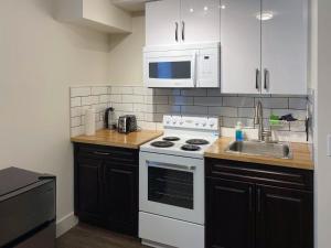 cocina con fogones blancos y fregadero en Calming 1bedroom Units With Balcony And City View, en Edmonton