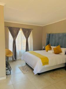 a bedroom with a large white bed with yellow pillows at SERENE ACCOMMODATION PALACE in Bela-Bela +13 photos