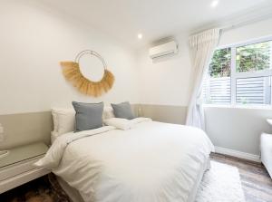 a white bedroom with a bed and a window at Secure, Peaceful Modern Cottage for Two in Durban