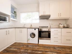 a kitchen with white cabinets and a washing machine at Secure, Peaceful Modern Cottage for Two in Durban