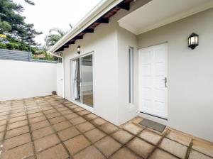 une maison blanche avec une porte de garage blanche dans l'établissement Secure, Peaceful Modern Cottage for Two, à Durban