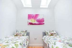 a bedroom with two beds and a purple flower on the wall at Superb Location - 'The Annexe' - at Ty Moel Isaf in Amlwch