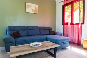 Sofá azul en la sala de estar con mesa de centro en Appart Maïté 3, en La Saline-Les-Bains