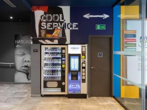 ibis budget Madrid Aeropuerto في مدريد: آلة بيع المشروبات الغازية في متجر مع طفل