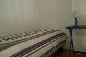 Bett in einem Zimmer mit einer Lampe auf einem Tisch in der Unterkunft Villa vacances N°23 à 100 mètres de la plage in Saint-Cyprien