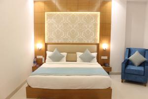 a bedroom with a large bed and a blue chair at Hotel Transit International- Aerocity Delhi Airport in New Delhi