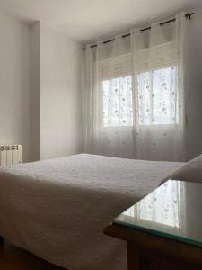 a white bedroom with a bed and a window at Apartamentos Fuente La Raja in La Iruela