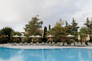 a large swimming pool with chairs and umbrellas at Village Heights Resort in Hersonissos