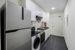 a kitchen with white cabinets and a washer and dryer at Studio Huge Balcony Loreto 1 Damac Hills in Dubai Marina