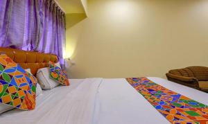 a bedroom with a bed with colorful pillows on it at FabExpress Jayshree in Mumbai