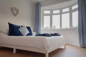 a bedroom with a bed with blue pillows and a window at East Wittering fun, sun and sea in West Wittering