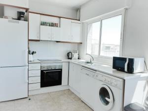 Una cocina blanca con lavadora y secadora. en ÁTICO ZONA VENEZIOLA, LA MANGA en La Manga del Mar Menor