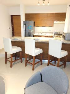 a kitchen with a counter with three chairs and a kitchen counter at Serena 4 in Punta Cana