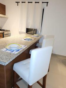 a kitchen with white chairs and a counter with plates on it at Serena 4 in Punta Cana