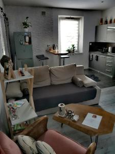 ein Wohnzimmer mit einem Sofa und Tischen sowie eine Küche in der Unterkunft Urocze studio w sercu Cieplic in Cieplice Śląskie Zdrój