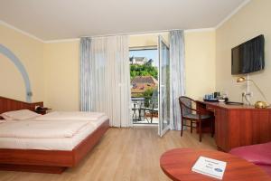 ein Hotelzimmer mit einem Bett, einem Schreibtisch und einem Balkon in der Unterkunft Land-gut-Hotel BurgBlick in Bad Kreuznach