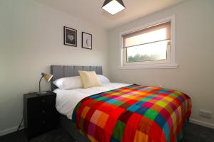 a bedroom with a bed with a colorful blanket at Signature - Salisbury House in East Kilbride