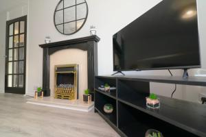 a living room with a fireplace and a flat screen tv at Signature - Salisbury House in East Kilbride