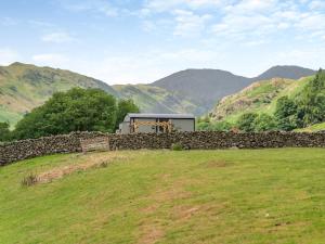 ein Gebäude hinter einer Steinmauer auf einem Feld in der Unterkunft 1 bed in Patterdale 85532 in Deepdale