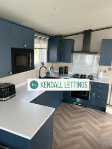a kitchen with blue cabinets and a white counter top at Sea View Lodge in Selsey +17 photos