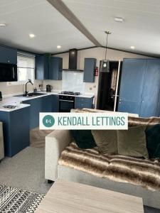 uma cozinha com armários azuis e um sofá num quarto em Sea View Lodge em Selsey