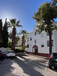 a parking lot in front of a building with palm trees at Apartamento Aperitivo in Tavira