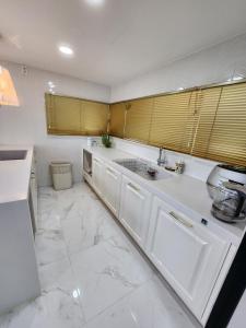 a kitchen with white cabinets and a marble floor at HANI Haus in Jeju