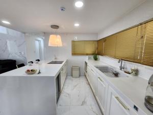 uma cozinha branca com um lavatório e um balcão em HANI Haus em Jeju