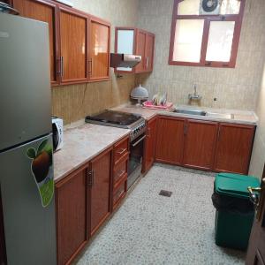 a kitchen with wooden cabinets and a stainless steel refrigerator at العين الهيلي مصباح بيت14 in Al Ain