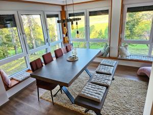 una sala da pranzo con tavolo, sedie e finestre di Kuća za odmor Šumska vila a Duga Resa