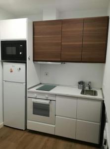 y cocina con fregadero, microondas y nevera. en Apartamento PB 30min Sagrada Familia, 10 min playa en Badalona