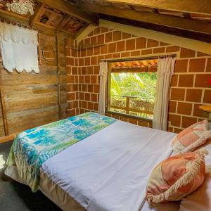 Cama en habitación de ladrillo con ventana en Casa por temporada a 250mts da praia, en Santa Cruz Cabrália