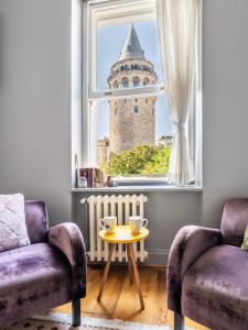 a room with two chairs and a window with a tower at Historical Apt. with Galata Sea View/Turkish Hamam in Istanbul
