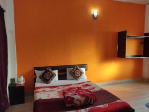 a bedroom with a bed with an orange wall at THE MYSTIC FOREST-A TEA GARDEN RESORT in Mādāri Hāt