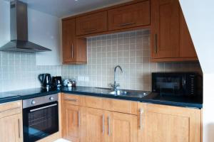 a kitchen with wooden cabinets and a sink and a microwave at *New* 2-Bed Modern Apartment in Burton upon Trent