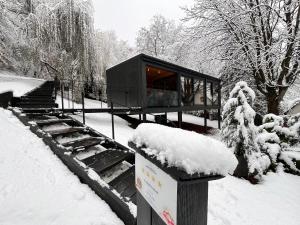 un edificio negro en la nieve con nieve. en Blackbox House Noszvaj, en Noszvaj