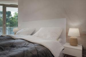 a white bedroom with a bed and a lamp at Apartament Premium PINEA 107 in Pobierowo