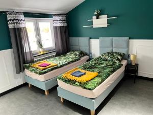 two beds in a room with green walls at Pokoje Gościnne "Cyprian" in Siedlce