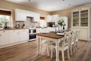 eine Küche mit einem Holztisch und weißen Schränken in der Unterkunft Willow Cottage in Cockburnspath
