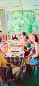 grupa ludzi siedzących przy stole z jedzeniem w obiekcie Felicity Inn w mieście Ella