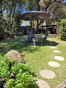 a table and chairs under an umbrella in a yard at Riverbush Lodge Guesthouse in Parys