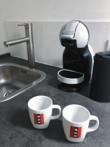 two coffee cups on a counter next to a kitchen sink at All-in Penthouseroom in Amsterdam